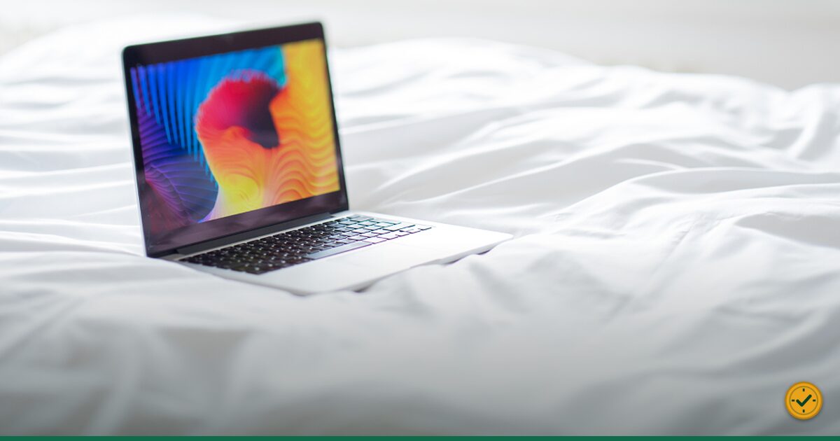 Open laptop resting on white bedding